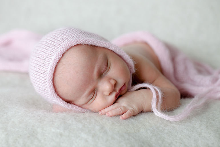newborn baby photos of baby in pink on neutral background